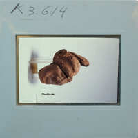 Terracotta figurine face fragments partially restored 3/4 view on stand K3.614.