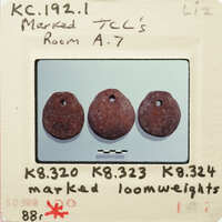 Three antique loom weights on display.