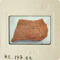 Ancient red clay pottery artifact on display.