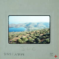 A vintage photograph of a scenic landscape with mountains, a lake, and greenery.