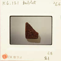 A photograph of an old slide featuring a small, irregularly shaped rock with red and brown hues.