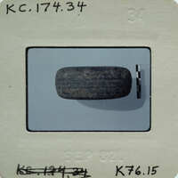 A photograph of a small stone object on a white surface.