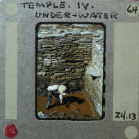 A man working on a stone structure underwater, with a dated film strip border.