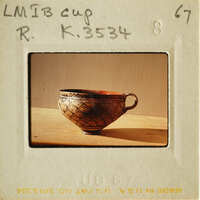 An antique cup with intricate designs on a wooden surface.