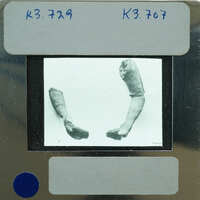 Black and white image of a film clapperboard with a picture of two human bones on it.