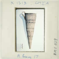 Ancient artifact on display, possibly a clay pottery piece with handle and markings.