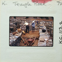 Workers constructing a stone wall with shovels and wheelbarrows.