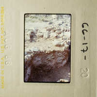 This is an image of a slide showing an archeological site with stone ruins and rubble, taken from a low angle.