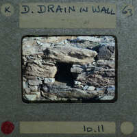 Picture of a stone wall with a hole, displayed on an old film strip.