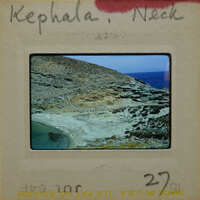 A slide of a rocky coastline with the sea, labeled "Kephala Neck" on its border.