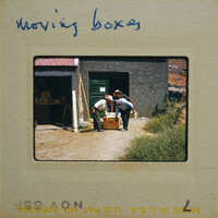 Two men moving a large wooden crate on a dirt road.