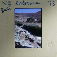 A vintage photograph of a stone-paved path with mountains in the background, displayed on an old film strip.