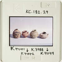 Old pottery displayed on a white surface, with labels and numbers written on the photo.