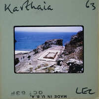 Photo of a coastal landscape with blue water, rocky terrain, and ruins.
