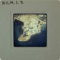 Aerial photograph of a coastal area with buildings and water.