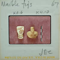 Two small, ancient objects on a white surface with labels.