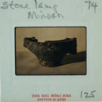 An old clay pot with a handle, photographed on a white background and labeled with handwriting.