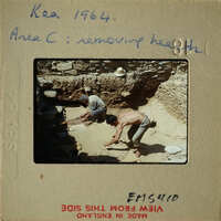 Two men working on an archaeological site, excavating and removing dirt with shovels.