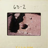 A photograph of an archaeological site with exposed ruins and a pottery shard.