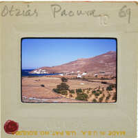 Old photograph of a coastal landscape with mountains, houses, and trees.