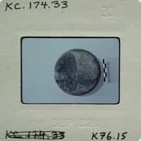 A small, round object on a film strip with white borders and black lines.