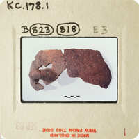 A close-up photo of an object, possibly pottery or ceramic, with visible texture and cracks.