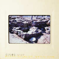 This is an image of a stone structure, possibly ruins, with a rocky landscape in the background.