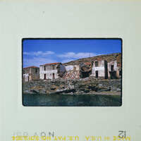 Abandoned buildings near a body of water, possibly an old fishing village.