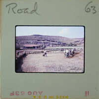 A group of people working on a dirt road with mountains in the background.