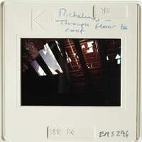 Old photograph showing interior with exposed wooden beams and rafters, possibly from an attic or roof space.