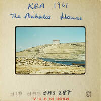 A photograph of an island with a house on top, surrounded by water and rocks.