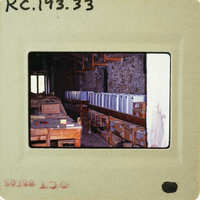 A photograph of a workshop with wooden benches and various tools, taken from an old Polaroid or instant camera.