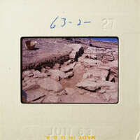 Stone ruins with scattered rocks and debris, possibly an archaeological site.