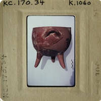 A photograph of an ancient artifact resembling a human head with teeth, possibly a sculpture or mask.