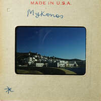 A photograph of an old slide depicting a coastal village with white buildings and a body of water, labeled "Mykonos".