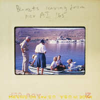 A group of people standing by a body of water with boats, possibly preparing to board or just disembarked.