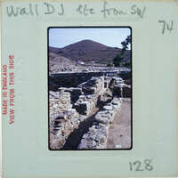 A photograph of a stone ruins with mountains in the background, enclosed within an old photo album page.