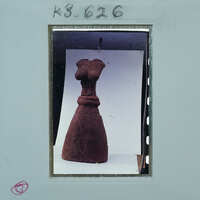 Ancient clay figurine of a woman on display with a label and number.