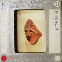 A small clay figurine of a face with an expression, displayed on a film strip card.