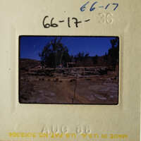 This is an image of a vintage photograph, possibly depicting a rural or desert landscape with a building and some trees.