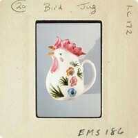 Decorative ceramic rooster mug with floral patterns on a blue background.