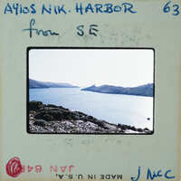 A vintage photo of a scenic harbor with water and mountains, enclosed in an envelope with handwritten notes on the back.