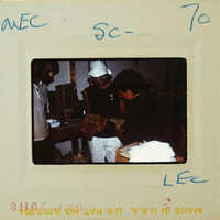 A vintage photo of a person with a hat and another individual, possibly taken from an old film reel.