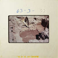 Ancient ruins with stone walls and a dirt floor, possibly from an archaeological site.