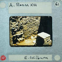 The image shows a photograph of an old, dilapidated room with stone walls and a brick floor, enclosed by a film strip border.