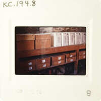 A photograph showing a room with boxes on shelves, taken from an angle where some of the boxes are obscured by the frame.