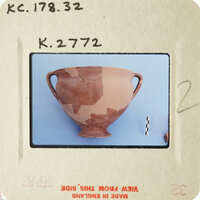 Ancient ceramic vase with visible cracks and missing pieces, displayed against a blue background.