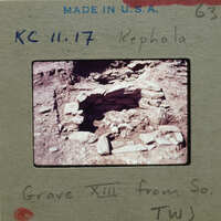 Ancient ruins with semi-circular stones and a dirt floor, probably from a grave.