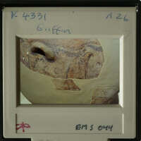 Ancient pottery with visible cracks and patterns, photographed against a blurred background.