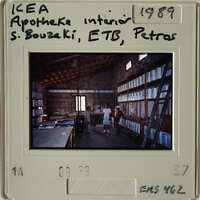 "Two people standing inside an industrial building with shelves and equipment."